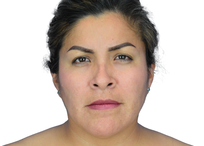 Close-up portrait of a woman with dark hair pulled back, neutral expression, wearing small earrings against a white background.