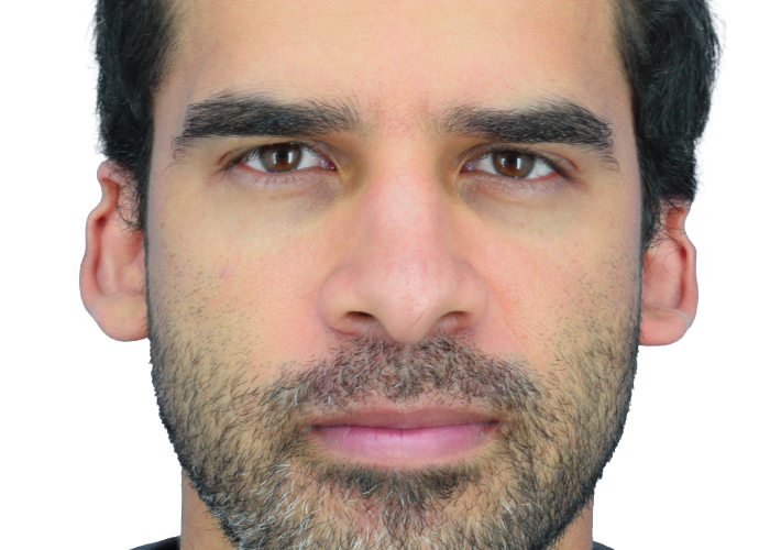 Close-up front-facing portrait of a man with dark hair and light stubble/beard.