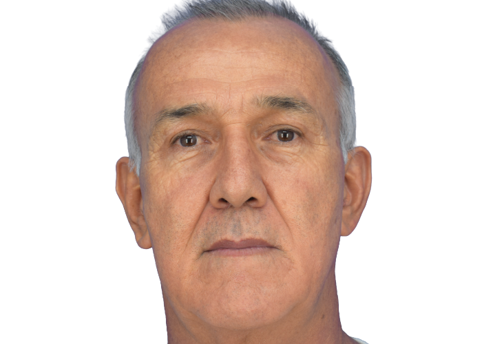 Close-up portrait of an older man with short gray hair, looking straight ahead against a white background.