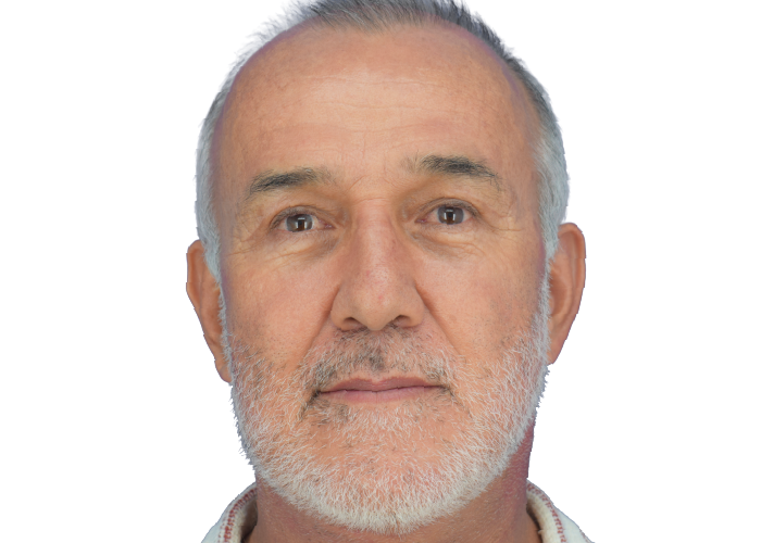 Close-up portrait of a gray-bearded older man looking straight ahead against a white background.