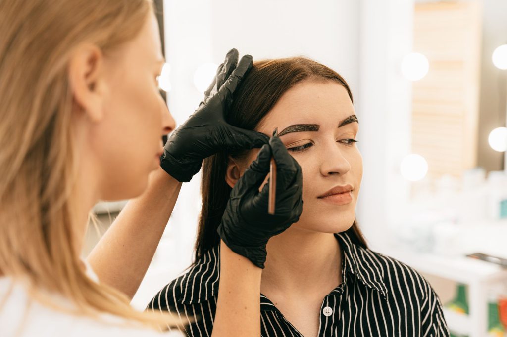 Profesional perfilando las cejas de una mujer
