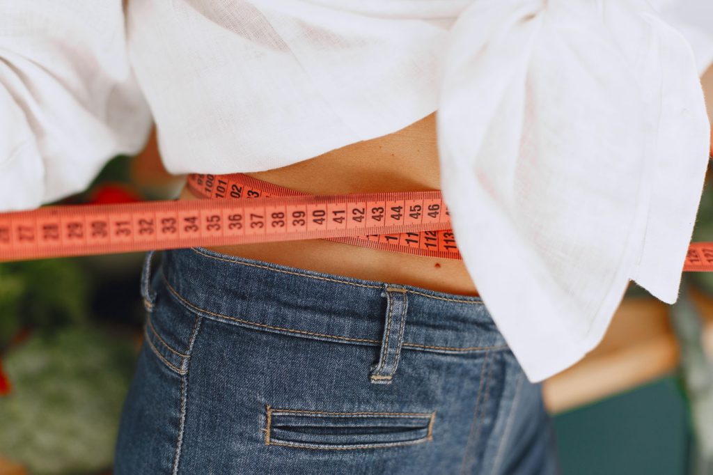 Mujer midiendo su abdomen con cinta métrica