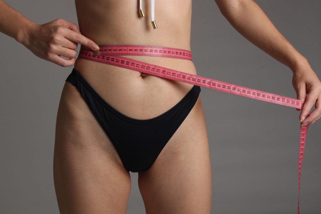 Mujer midiendo su cintura con cinta métrica